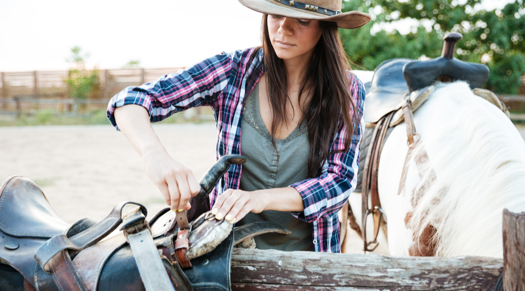 Woman adjusting horse saddle