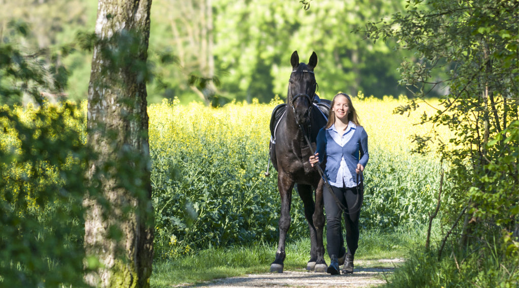 woman walking horse in field