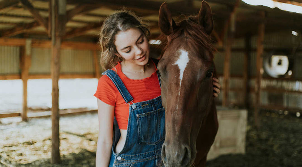  horse and young woman in barn